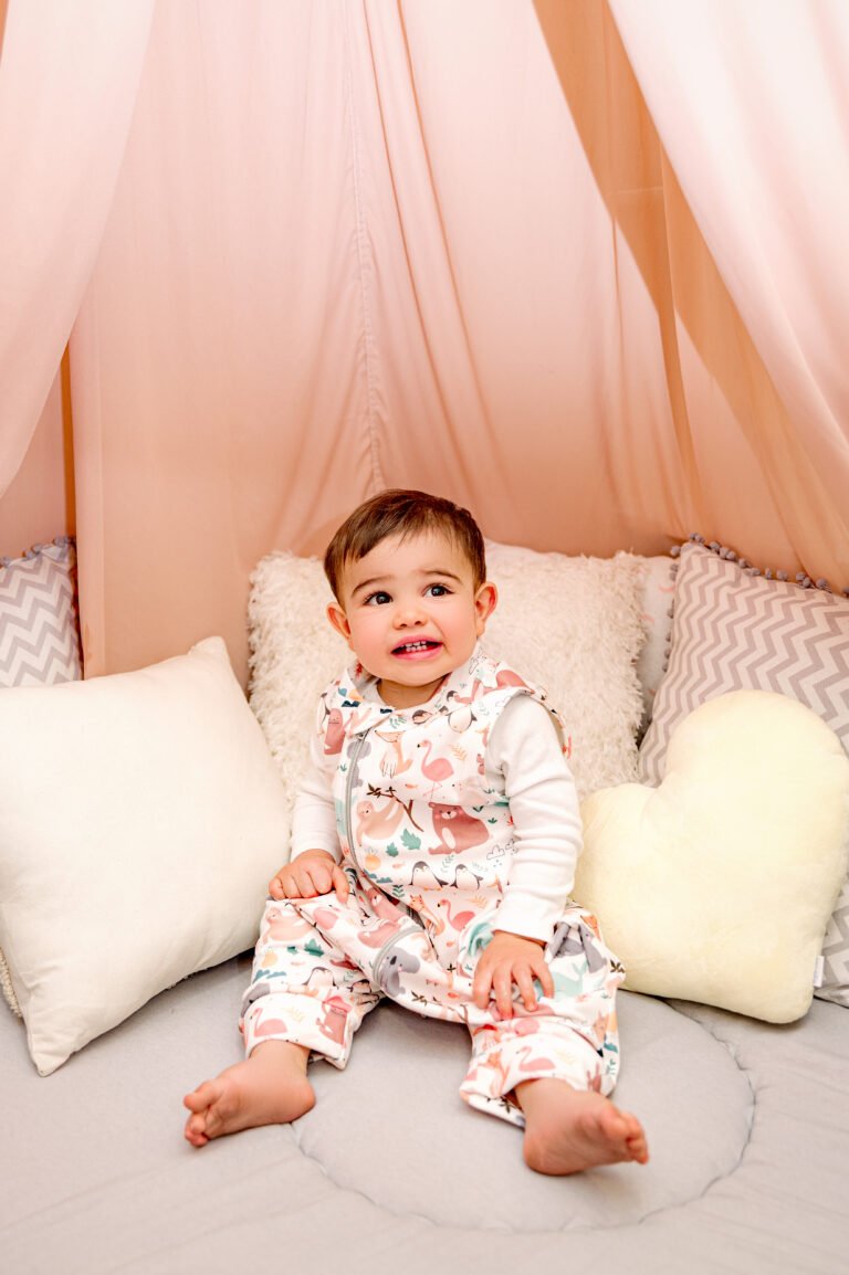 Bebé sonriendo con el Guardián de Sueños de BeBaby en su cama con dosel